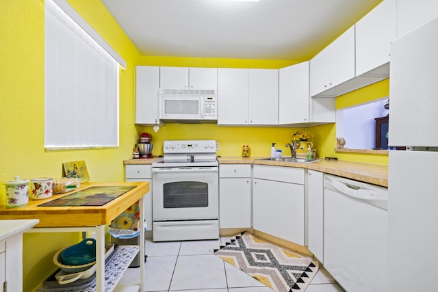 kitchen with light tile patterned floors, white cabinets, sink, and white appliances