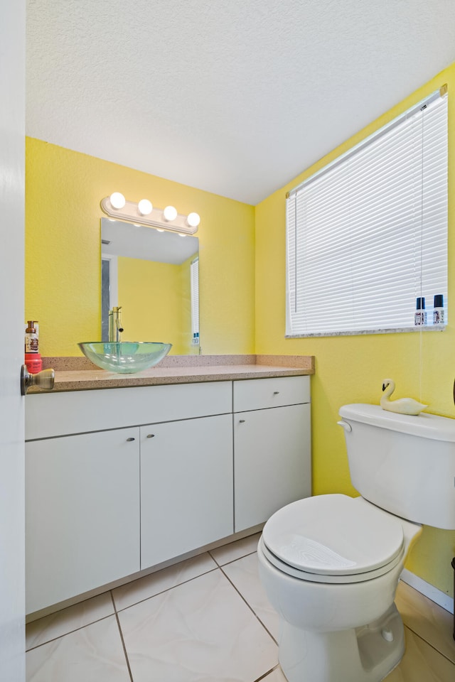 bathroom with a textured ceiling, vanity, and toilet