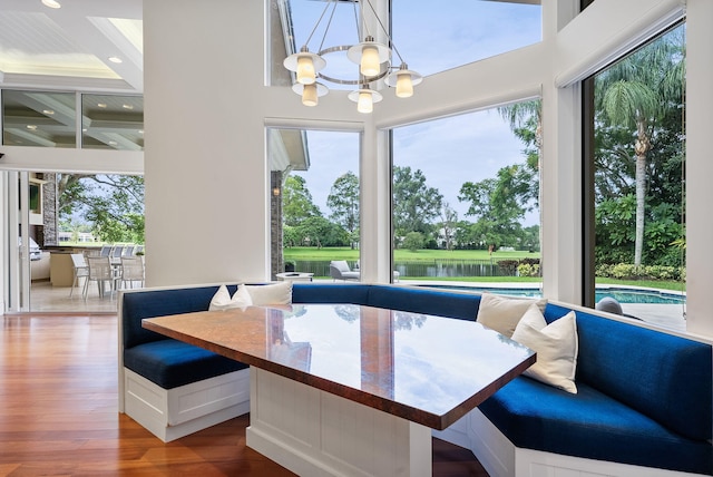 dining space featuring a water view, a chandelier, and hardwood / wood-style flooring