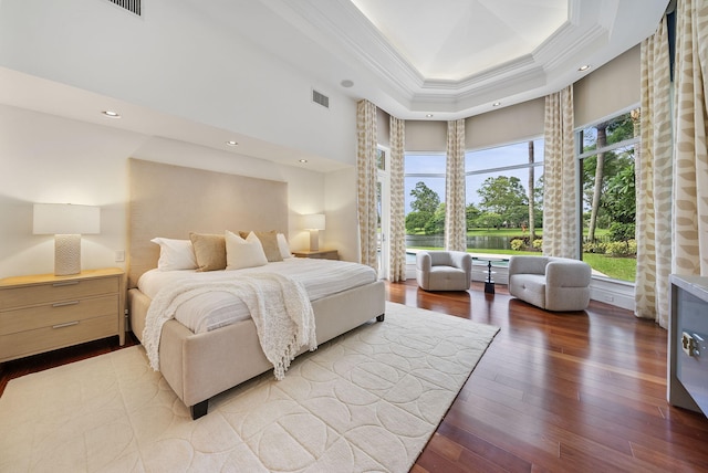 bedroom featuring ornamental molding, wood-type flooring, and a tray ceiling