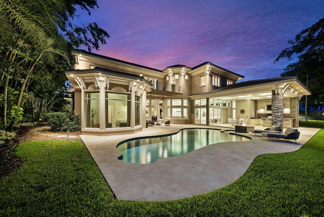 pool at dusk featuring a yard and a patio area