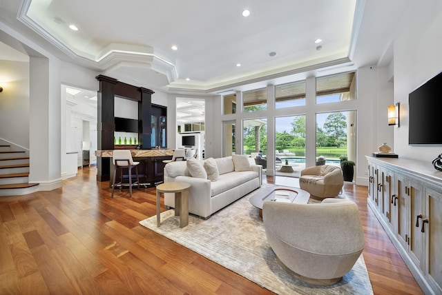 living room featuring crown molding, a raised ceiling, and hardwood / wood-style floors