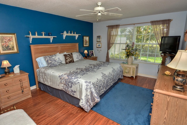 bedroom with ceiling fan, a textured ceiling, and dark wood-type flooring