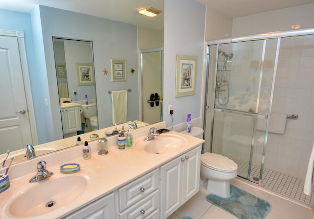 bathroom with tile patterned floors, vanity, toilet, and a shower with shower door