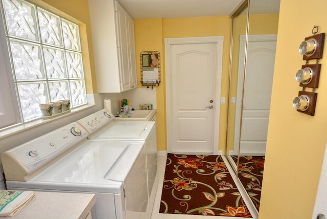 clothes washing area with cabinets, washing machine and dryer, and sink