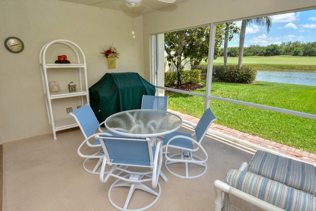 sunroom featuring ceiling fan and a water view