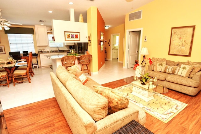 living room featuring ceiling fan, light tile patterned flooring, sink, and vaulted ceiling