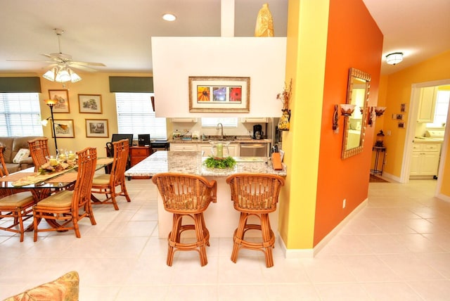 kitchen featuring a kitchen breakfast bar, a wealth of natural light, ceiling fan, and sink