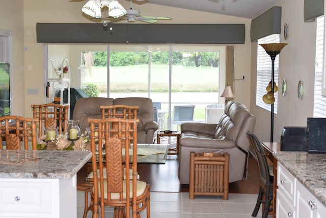 tiled dining room with ceiling fan and lofted ceiling