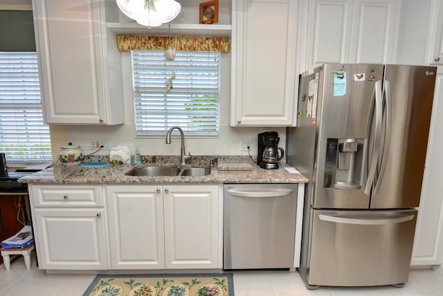 kitchen with light stone counters, sink, white cabinets, and appliances with stainless steel finishes