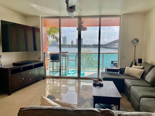 tiled living room with a water view, ceiling fan, and a wall of windows