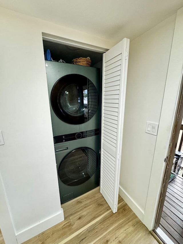 clothes washing area with stacked washer / dryer and light wood-type flooring