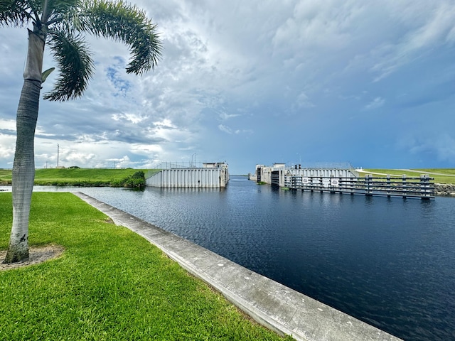 dock area with a lawn and a water view