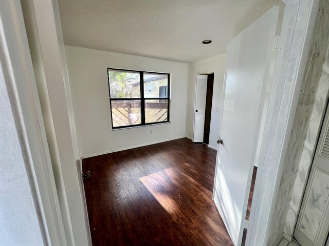 spare room with dark hardwood / wood-style flooring and a textured ceiling