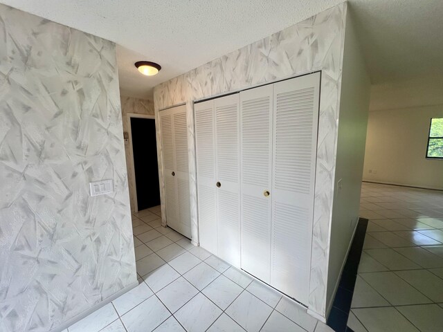 hall with light tile patterned floors and a textured ceiling