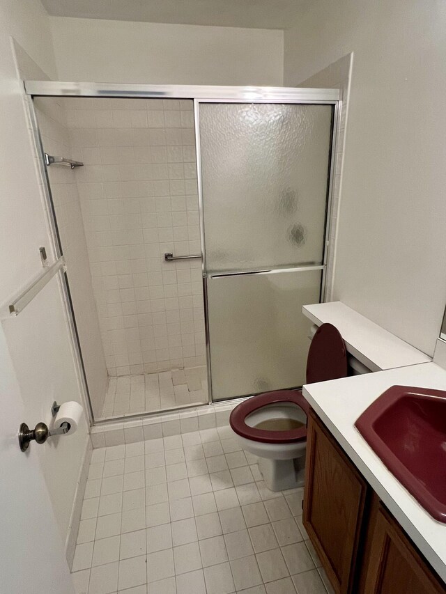 bathroom with tile patterned floors, toilet, a shower with door, and vanity