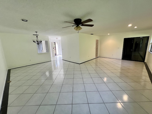 tiled empty room featuring a textured ceiling and ceiling fan with notable chandelier