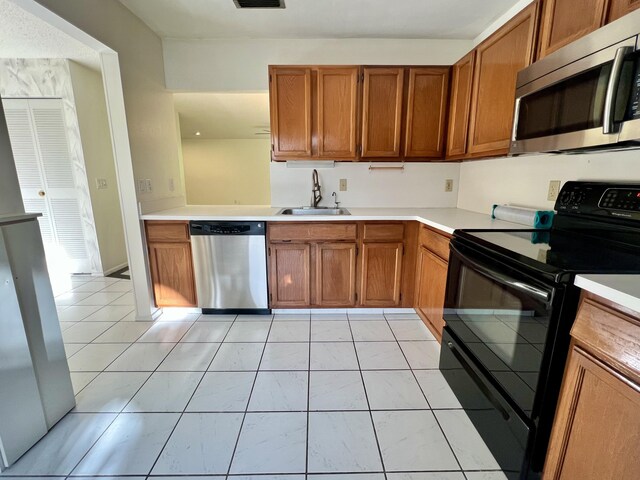 kitchen with stainless steel appliances, light tile patterned flooring, and sink