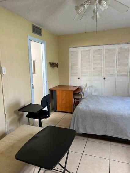 tiled bedroom with ceiling fan, a textured ceiling, and a closet