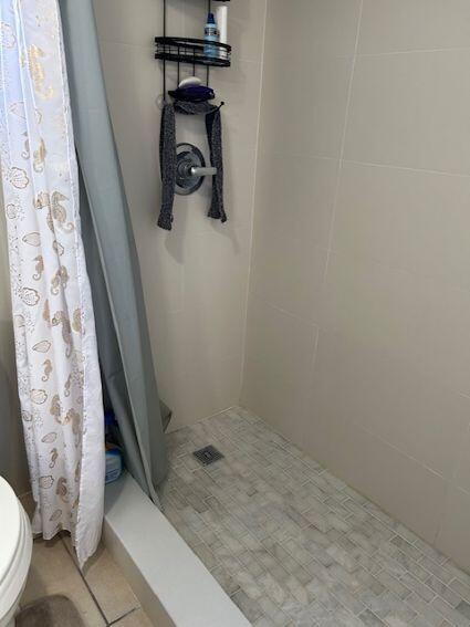 bathroom featuring tile patterned floors, toilet, and curtained shower