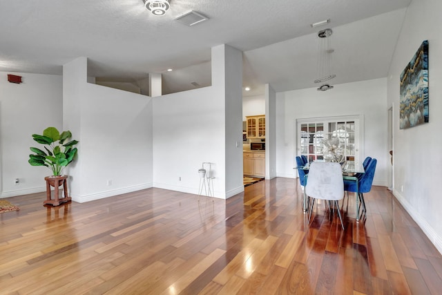 interior space with light wood-type flooring, a textured ceiling, and lofted ceiling