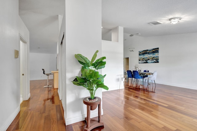 hall featuring a textured ceiling, high vaulted ceiling, and light hardwood / wood-style floors