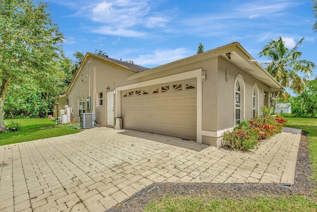 view of property exterior with a yard, a garage, and central AC