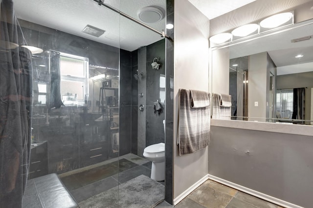 bathroom featuring a shower with door, vanity, toilet, and plenty of natural light