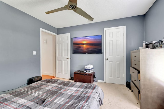 bedroom with light colored carpet, ceiling fan, and a textured ceiling