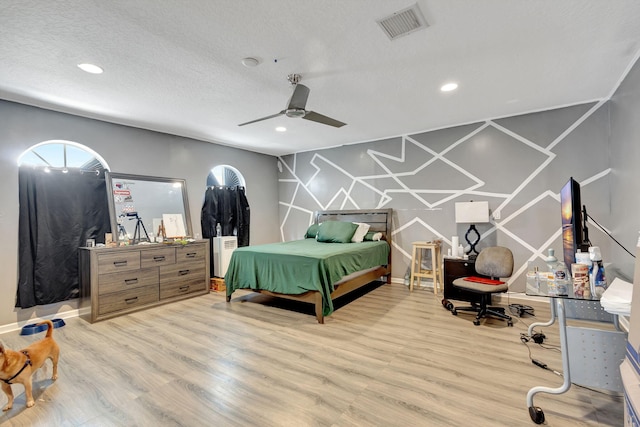 bedroom featuring ceiling fan, light hardwood / wood-style floors, and a textured ceiling