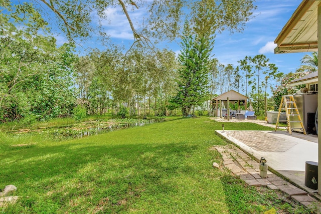 view of yard featuring a water view, a patio area, and a gazebo