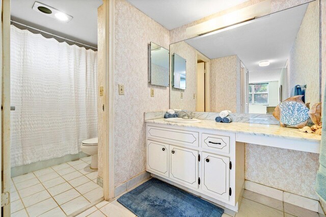 bathroom with a shower with shower curtain, vanity, toilet, and tile patterned floors