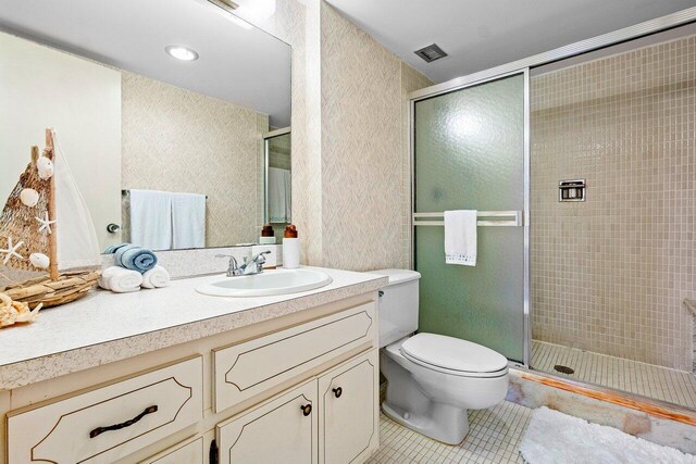 bathroom with vanity, toilet, tile patterned flooring, and a shower with door