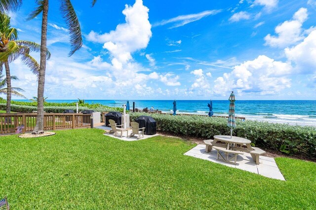 view of yard featuring a water view, a patio area, and a beach view