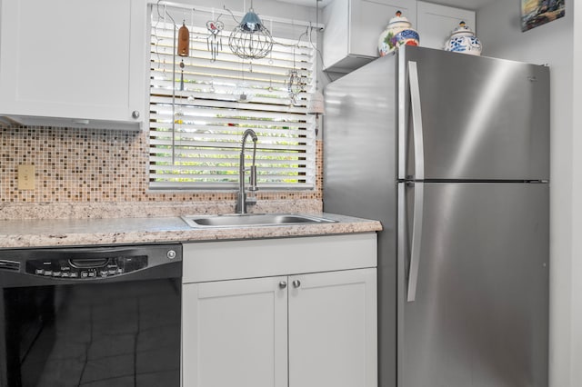 kitchen featuring white cabinets, stainless steel fridge, sink, black dishwasher, and decorative backsplash