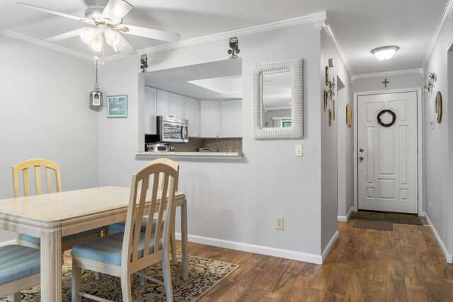 dining space with ceiling fan, dark hardwood / wood-style floors, and crown molding