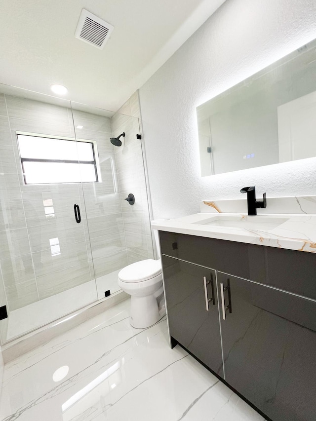 bathroom with vanity, a shower with shower door, and toilet