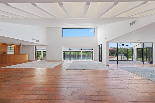 unfurnished living room with ceiling fan and a towering ceiling