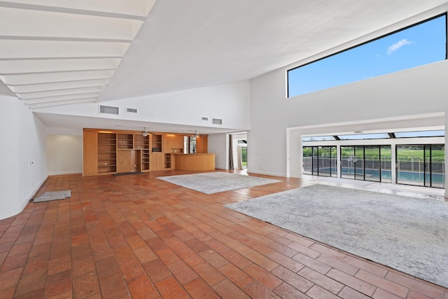 unfurnished living room featuring brick floor, visible vents, and baseboards