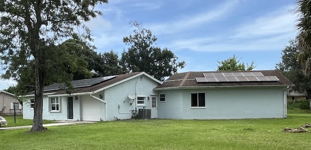 rear view of house featuring a yard, solar panels, and central AC