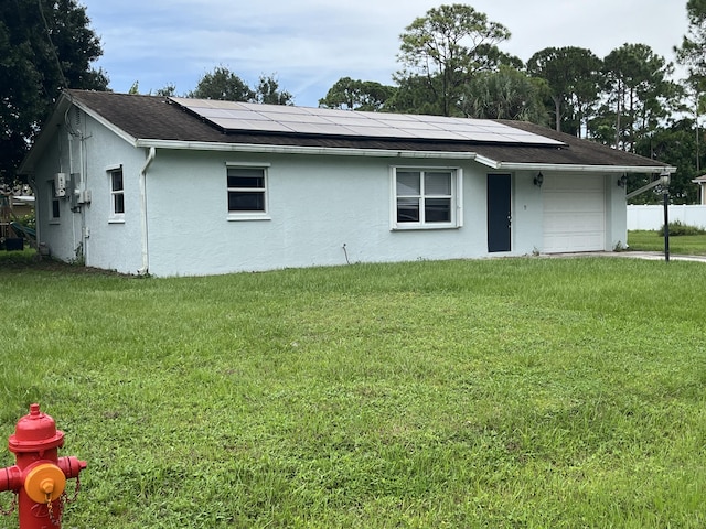 rear view of house with a yard and solar panels