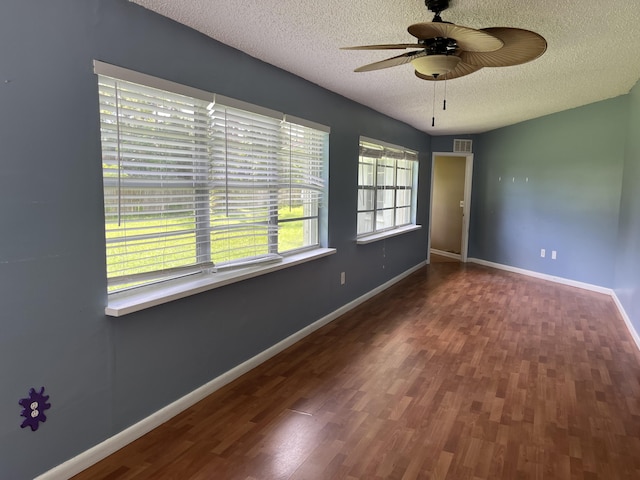 spare room with ceiling fan, a wealth of natural light, dark hardwood / wood-style floors, and a textured ceiling