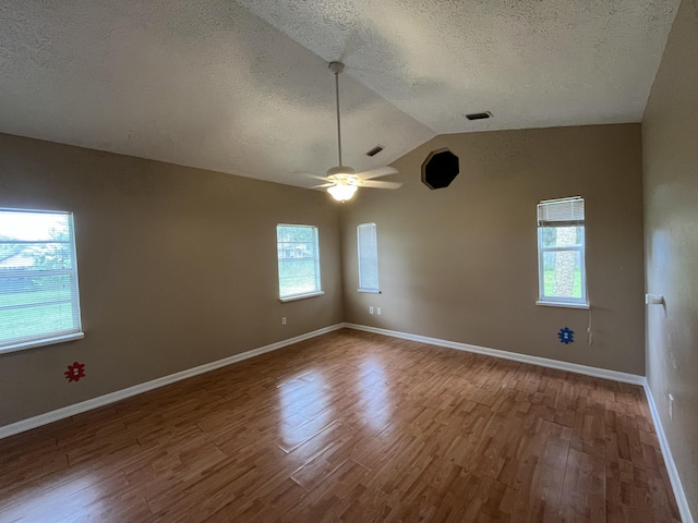 unfurnished room with lofted ceiling, ceiling fan, hardwood / wood-style flooring, and a textured ceiling