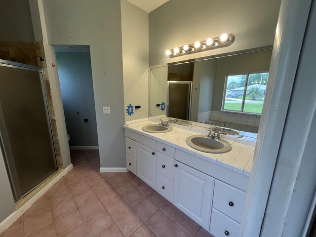 bathroom with tile patterned flooring, a shower with shower door, and vanity