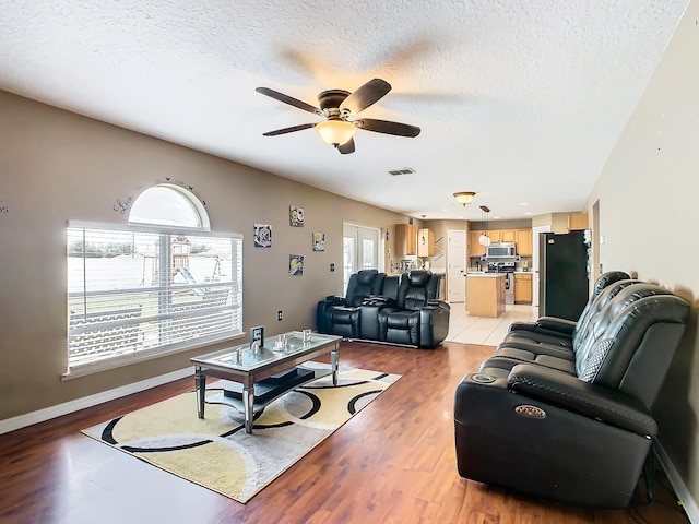 living room featuring a textured ceiling, light hardwood / wood-style floors, and ceiling fan