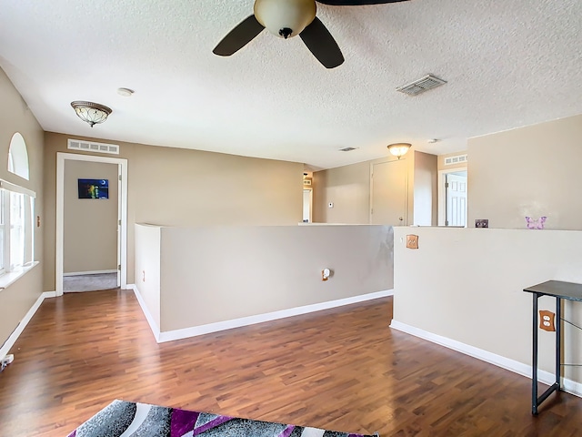 unfurnished living room with ceiling fan, a textured ceiling, and dark hardwood / wood-style floors