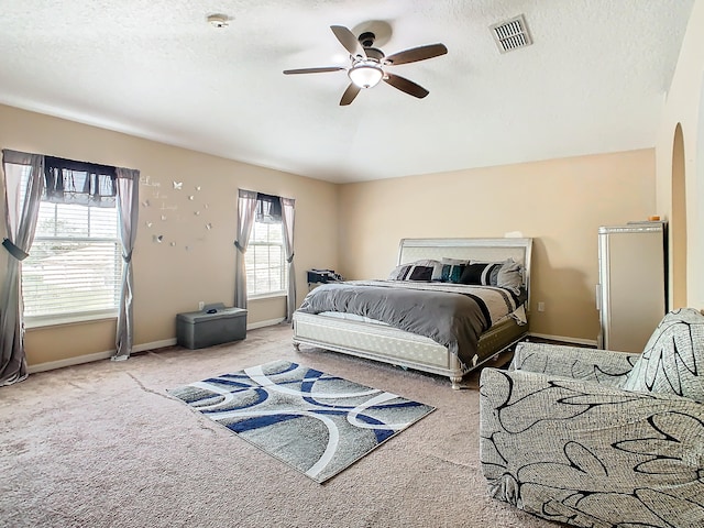 bedroom with a textured ceiling, ceiling fan, and light colored carpet