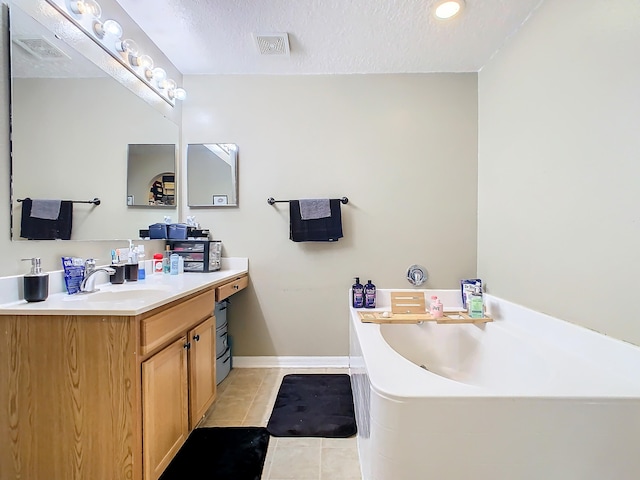 bathroom featuring vanity, a textured ceiling, a tub, and tile patterned floors