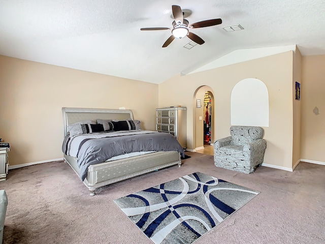 carpeted bedroom with a textured ceiling, vaulted ceiling, and ceiling fan