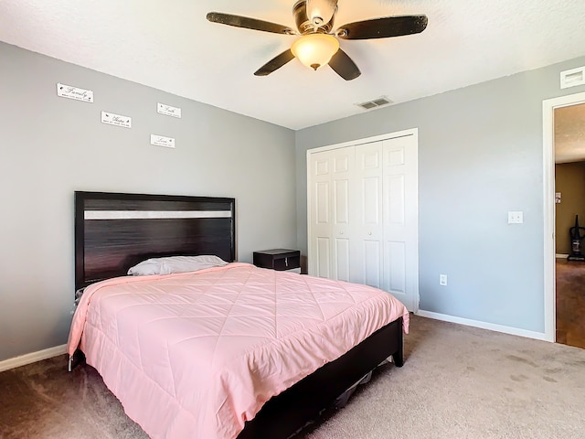 bedroom with dark colored carpet, ceiling fan, and a closet